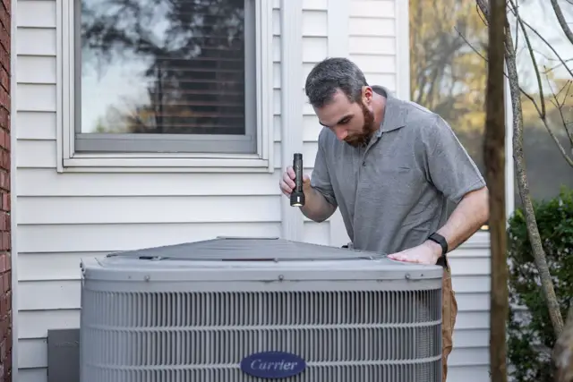 HVAC technician checking an outdoor AC unit